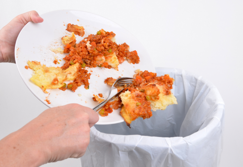 Free image from canva of leftover food being scraped into the bin