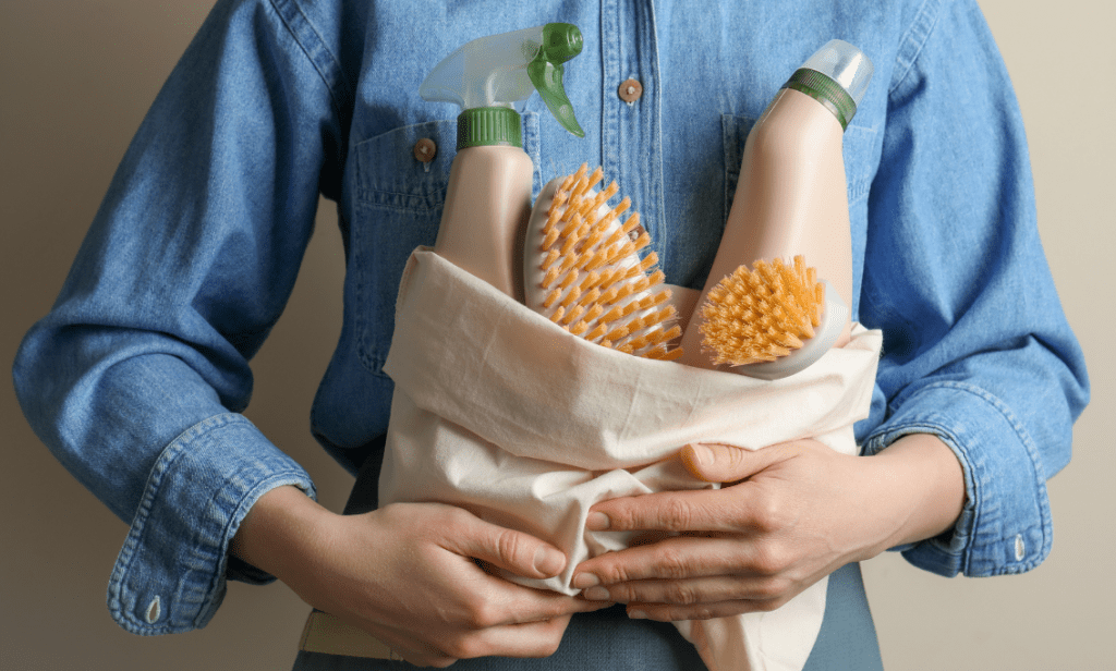 Eco Swaps - Image from Canva of a woman in a blue denim short holding some Eco Friendly Cleaning Products