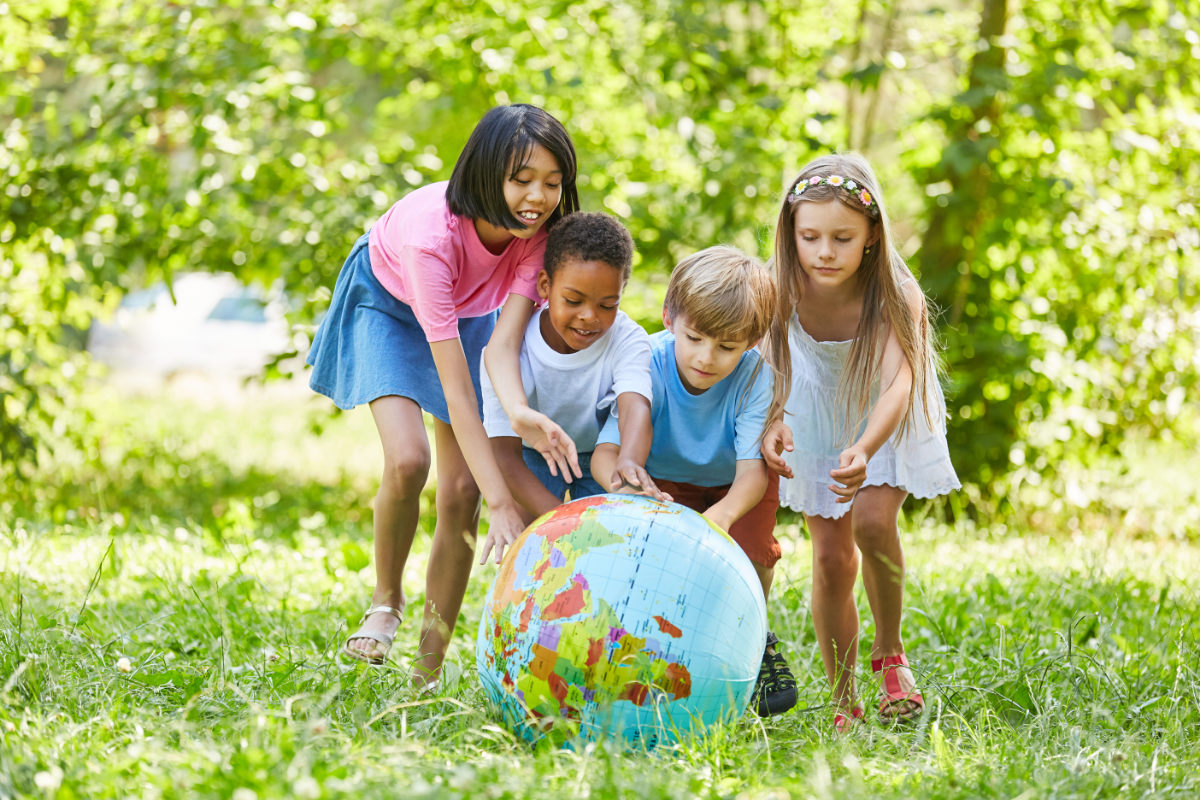 Teaching Kids About Sustainability - Group of kids playing with a ball that is a map of earth outdoors - Stock image from Canva