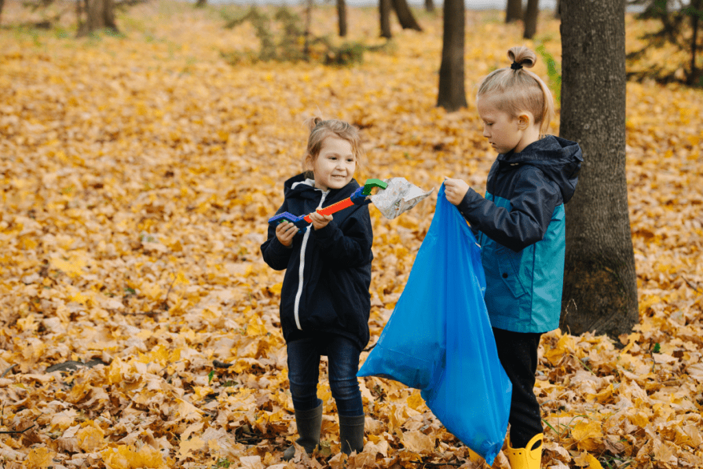 Teaching kids about sustainability - two kids in a park picking up litter with a grabby stick