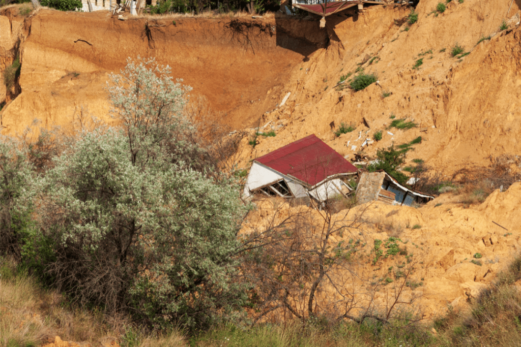 seismic phenomena - image of house collapsed in a landslide with exposed earth behind it