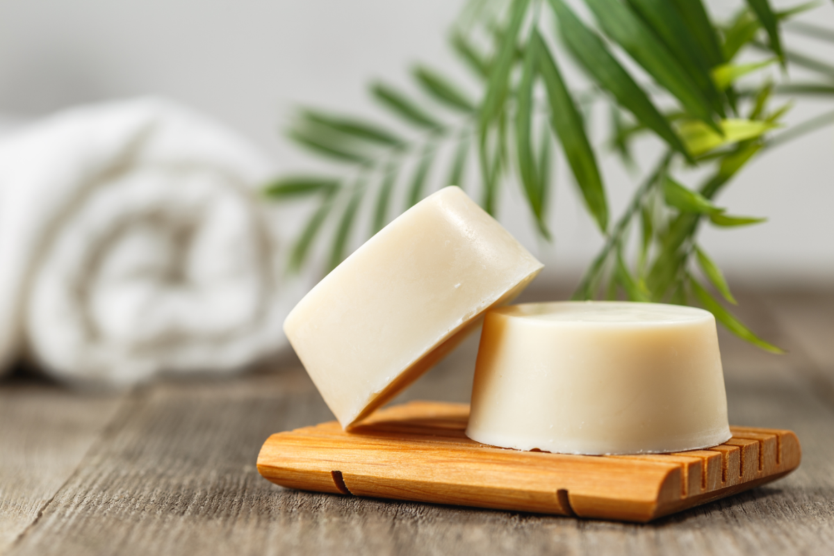 Zero-Waste Shampoo Bars on a Wooden Soap Dish with Greenery in the Background