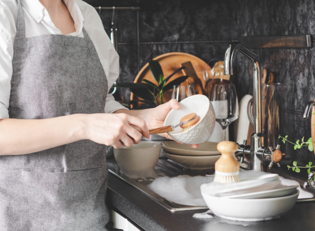 Zero Waste Dish Soap Bars - Stock Image from Canva of a woman washing dishes with a wooden brush in a high-end kitchen