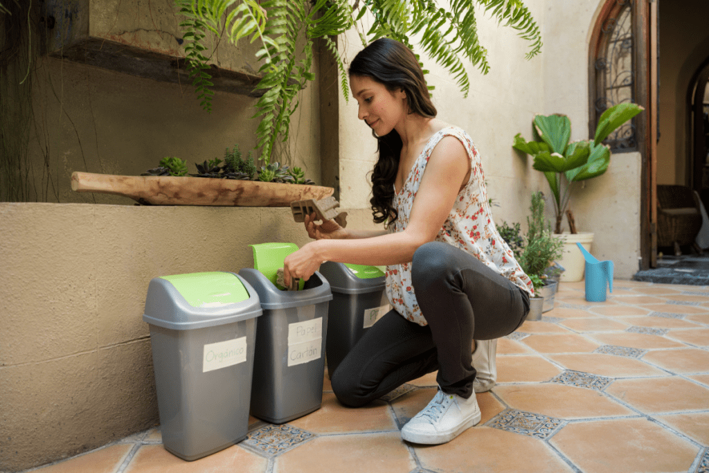 Sustainable Living - stock image from Canva of a woman putting paper into one of three recycling bins in her home
