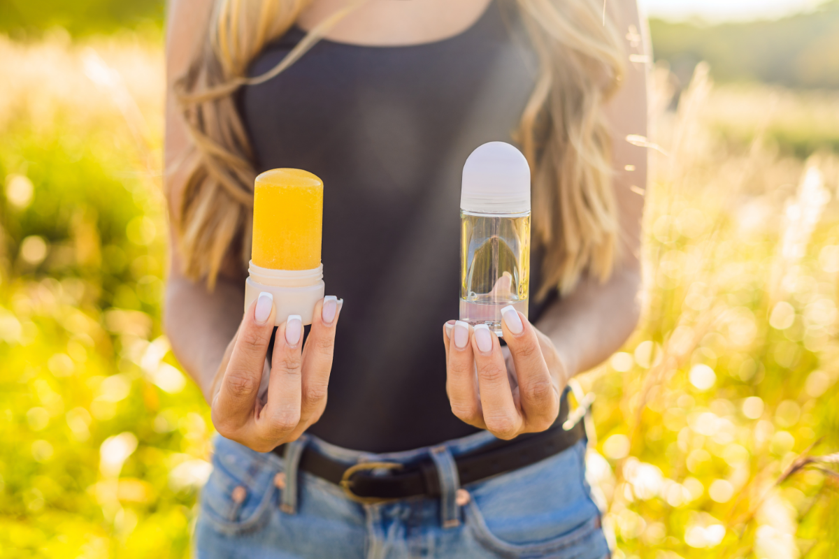 Eco-friendly Deodorant - Canva Stock Image of a woman outdoors holding a glass roll on bottle in one hand and a paperboard roll on in the other