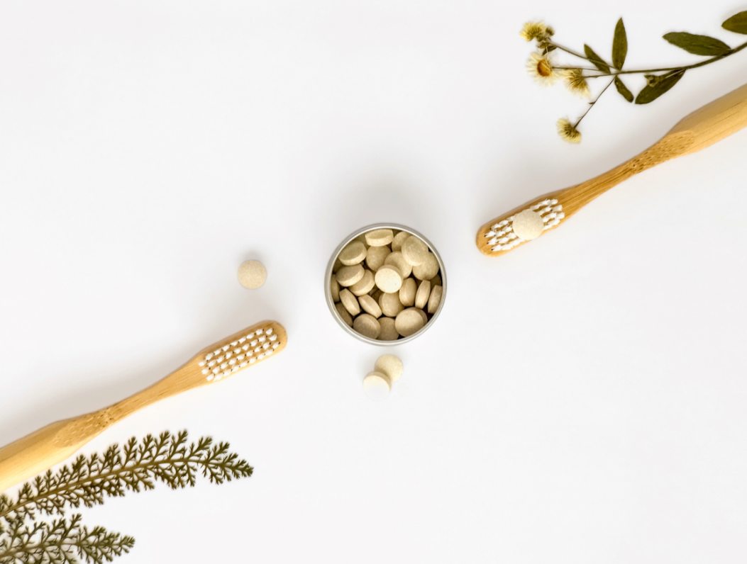Eco-friendly Toothpaste - Stock Image from Canva of two bamboo toothbrushes and a small tin of toothpaste tablets