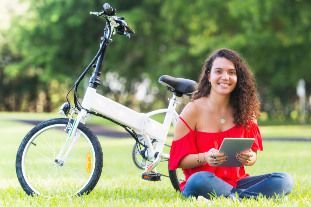 Green Living Tips for College Students- Female Students with Bicycle and a tablet sitting on the grass
