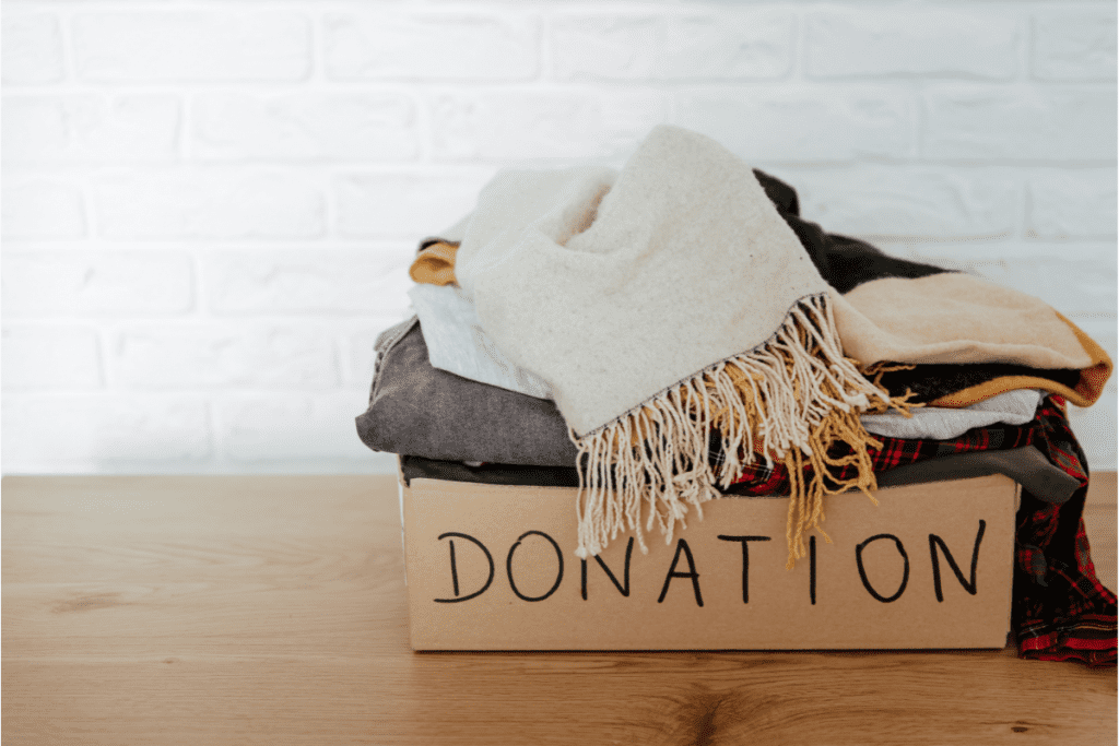 Sustainable decluttering - Image of clothing folded in a cardboard box labeled 'donation'