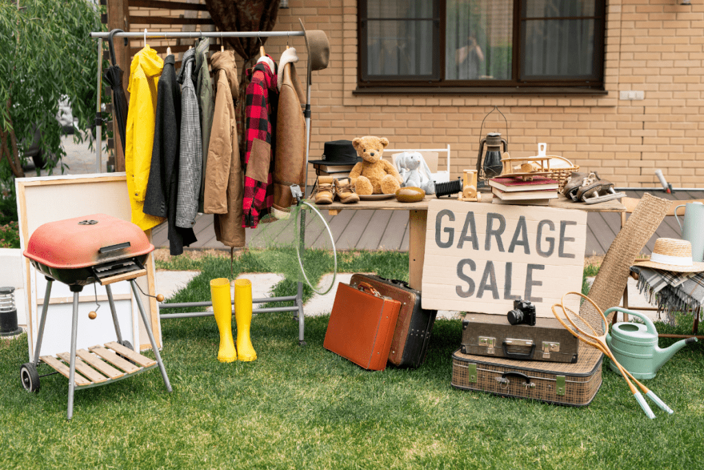 Sustainable decluttering - image of garage sale with items displayed on the lawn and a home made sign that says "garage sale"