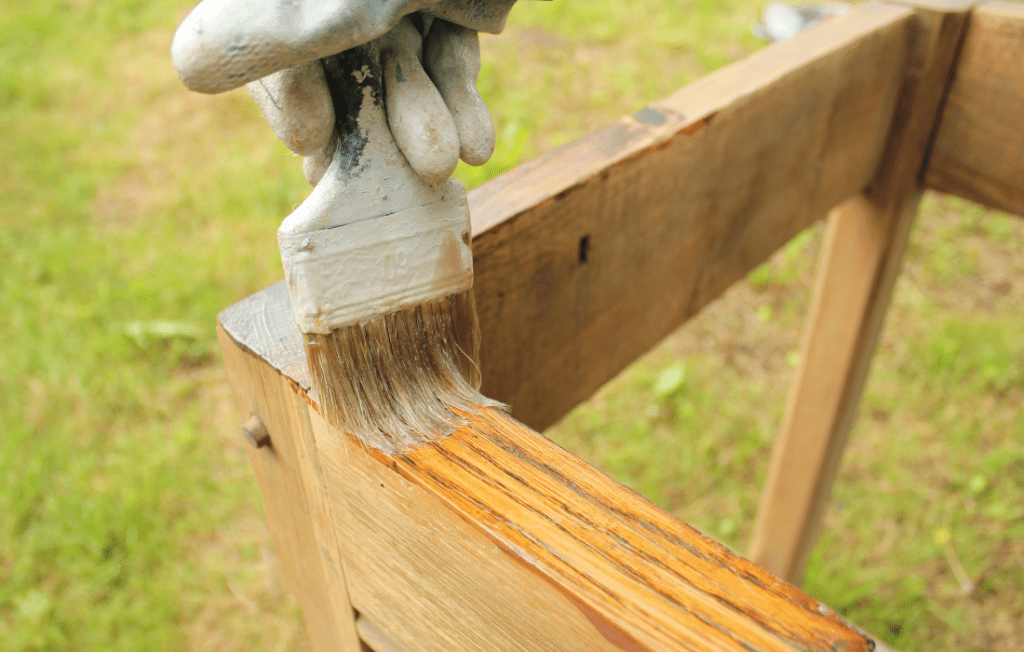 How to care for acacia wood - image of brush with varnish or oil being painted onto faded wood