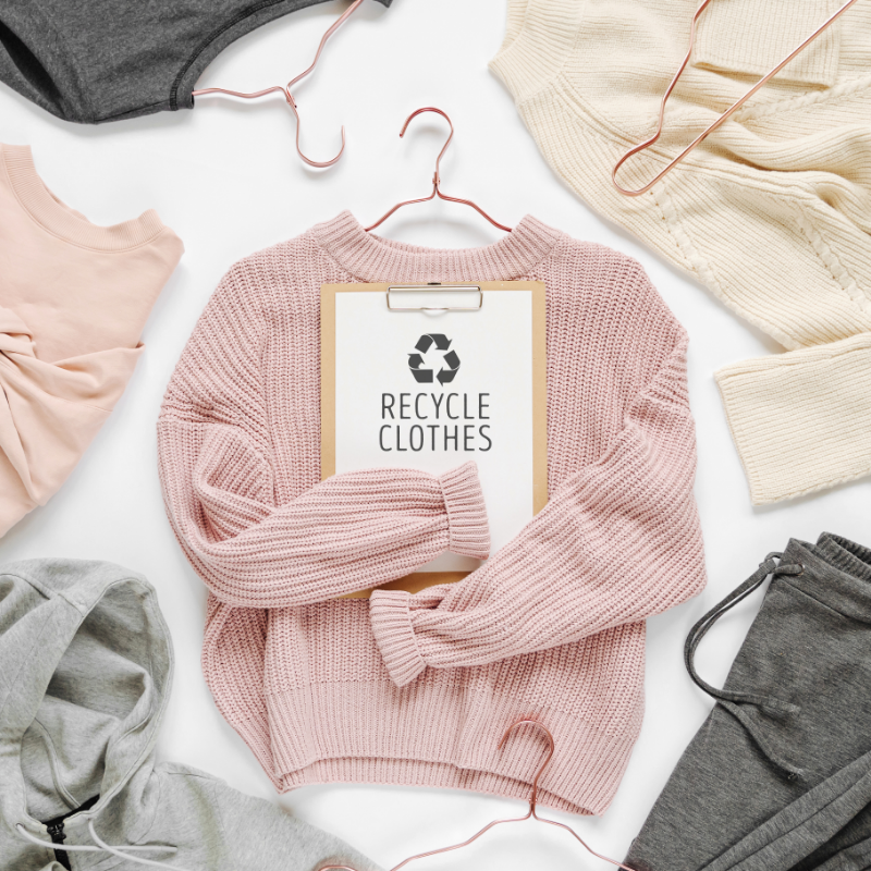 Sustainable fashion - image of a top view of women's clothing items and a sign that says "recycle clothing" on it