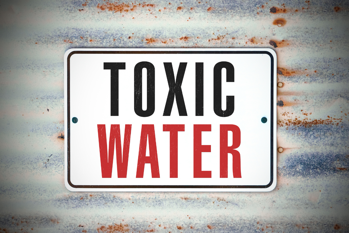 Image of a sign that says "toxic water" on a metal background