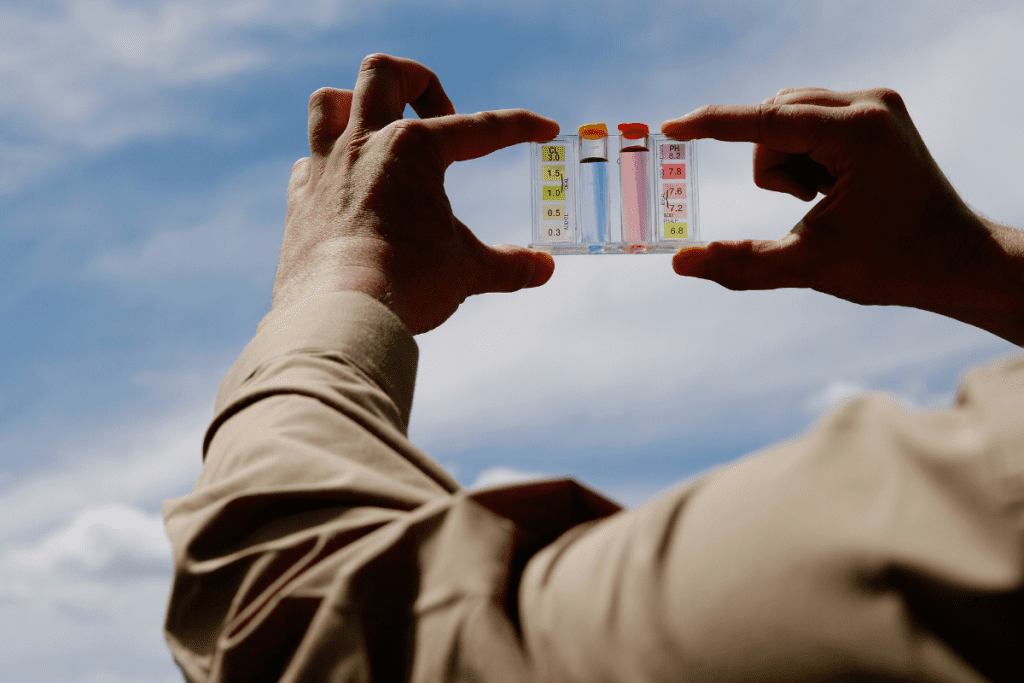 Image of a mans hands holding up vials of water in a home test kit to the light to see the colours