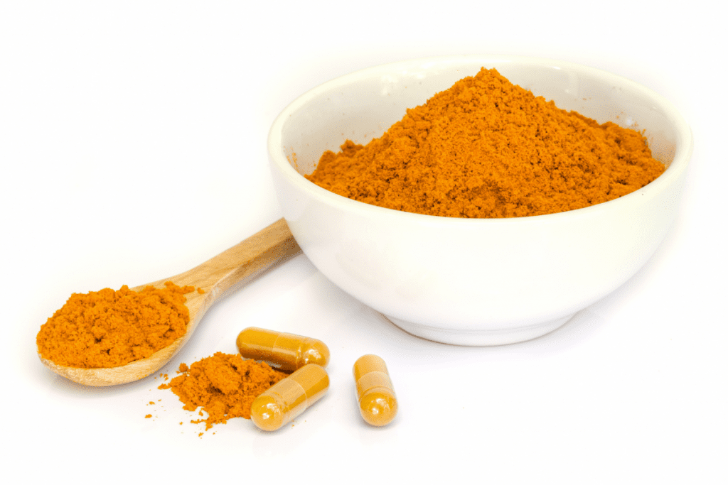 Herbs for Weight Loss - Turmeric powder in a bowl, with Turmeric capsules next to it