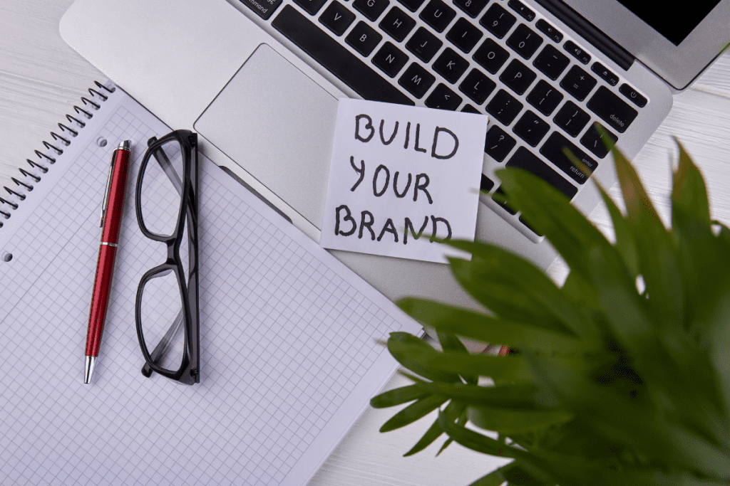Eco-friendly Business - concept image of a laptop, glasses and notebook with the sticky note that says "build your brand"
