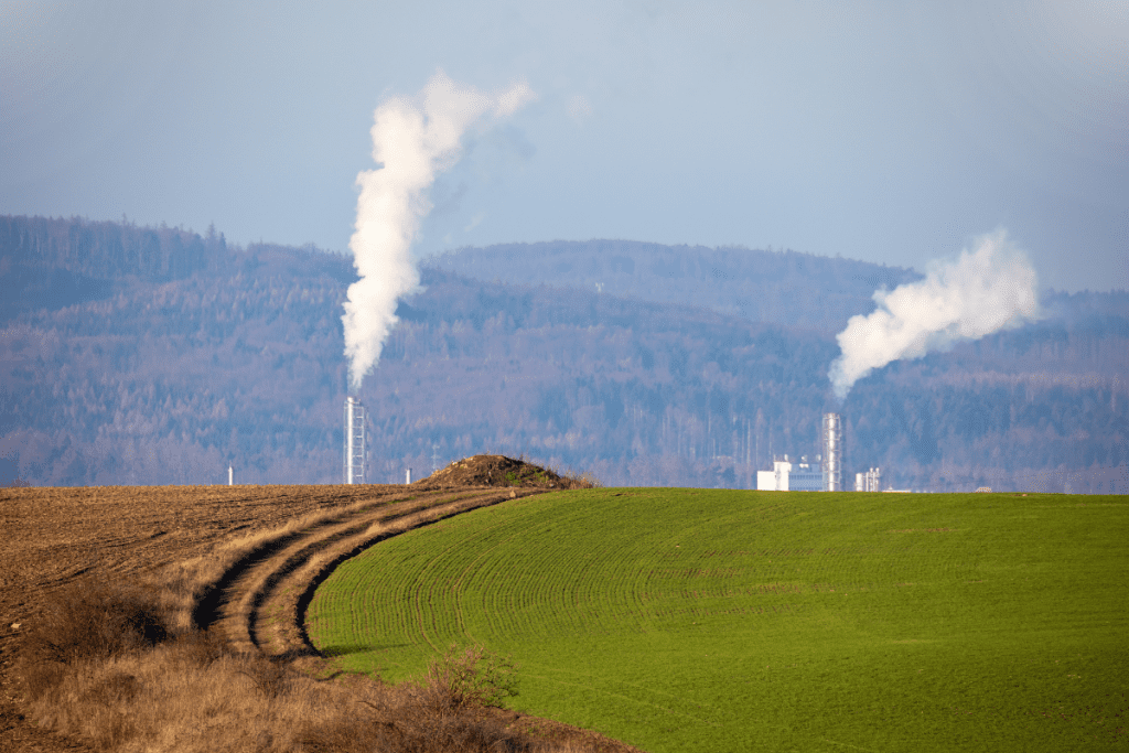 Image of green fields with smoke stacks in the background