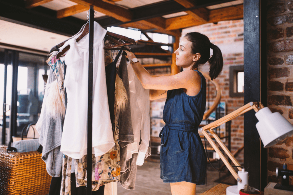 Woman looking at clothes in a rail in a trendy and modern-industrial looking thrift store