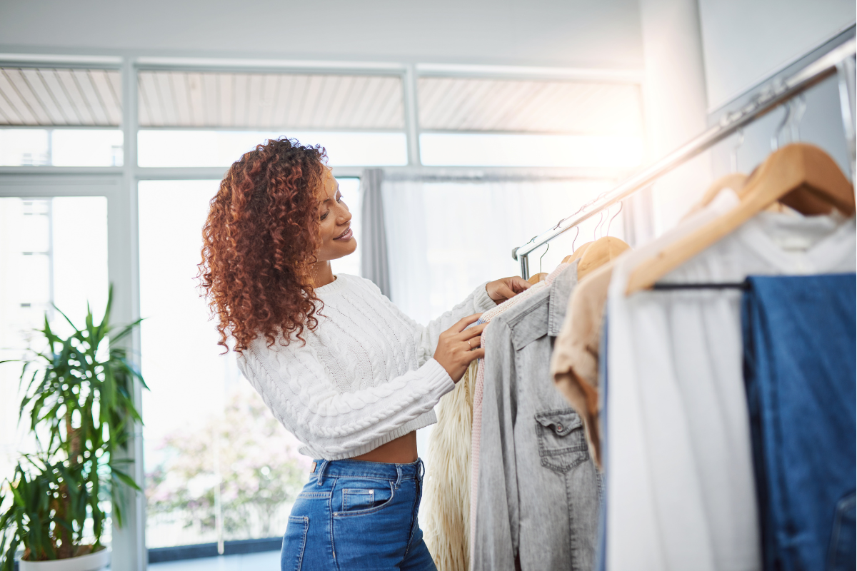 Sustainable Wardrobe Essentials - Stock feature image of a woman picking out clothes from a clothes rail