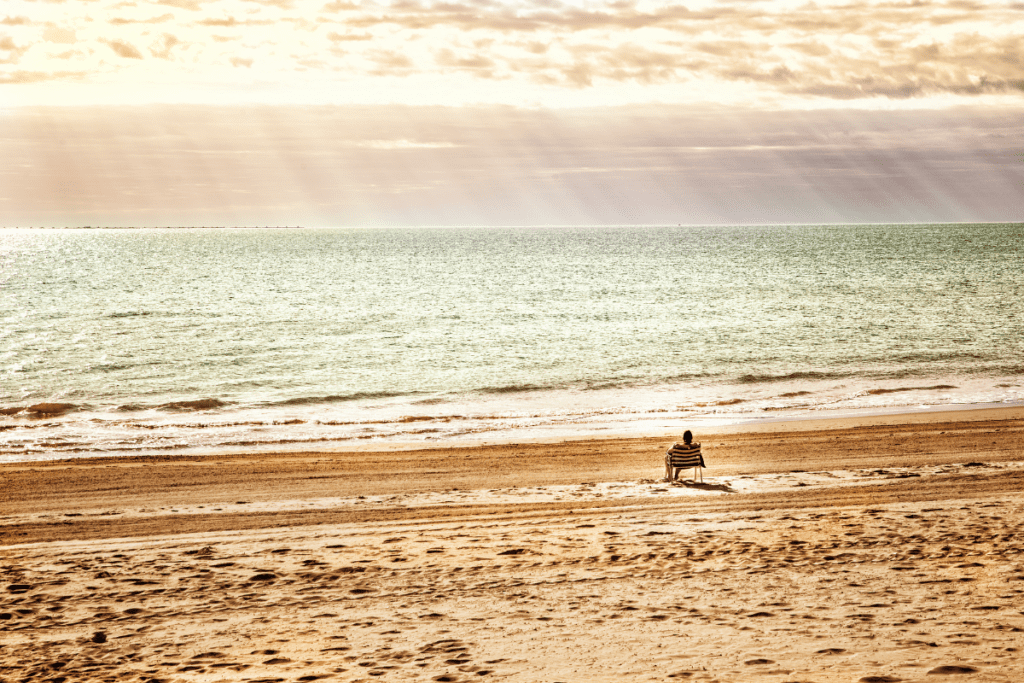 eco-friendly vacation - stock image from, canva of a person sitting in a deck chair on an empty beach