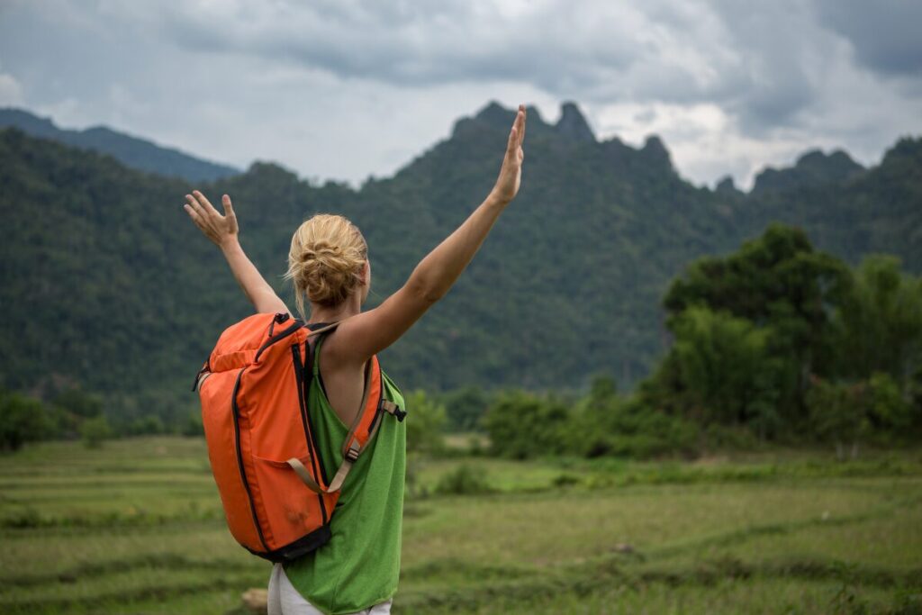 A female tourist with an orange bag facing a mountain view