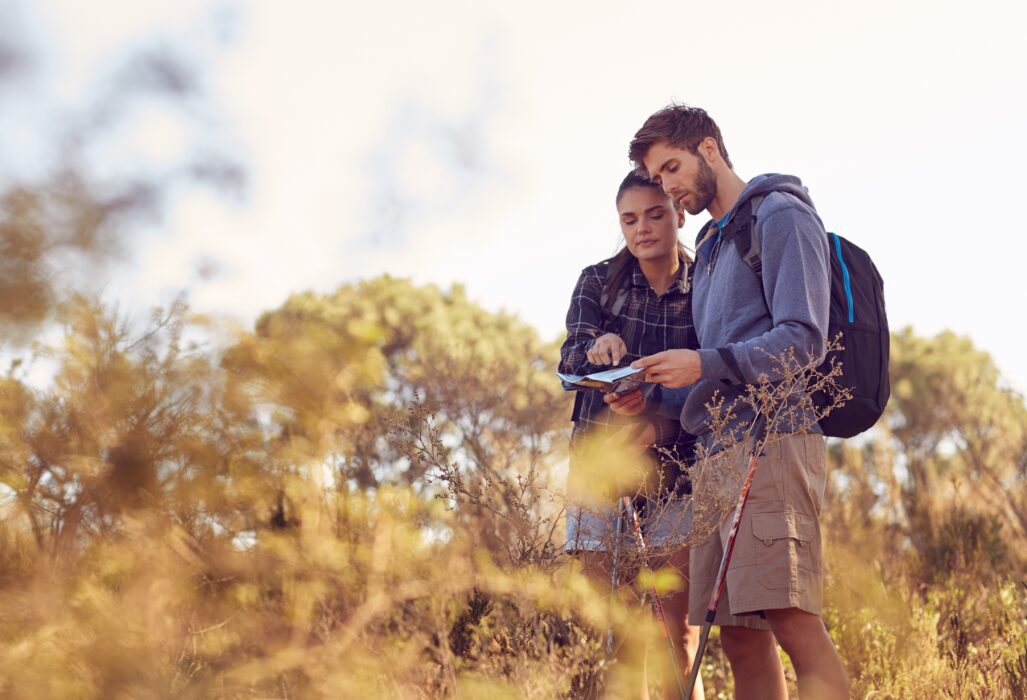 eco-camping - a couple in nature looking down at a map